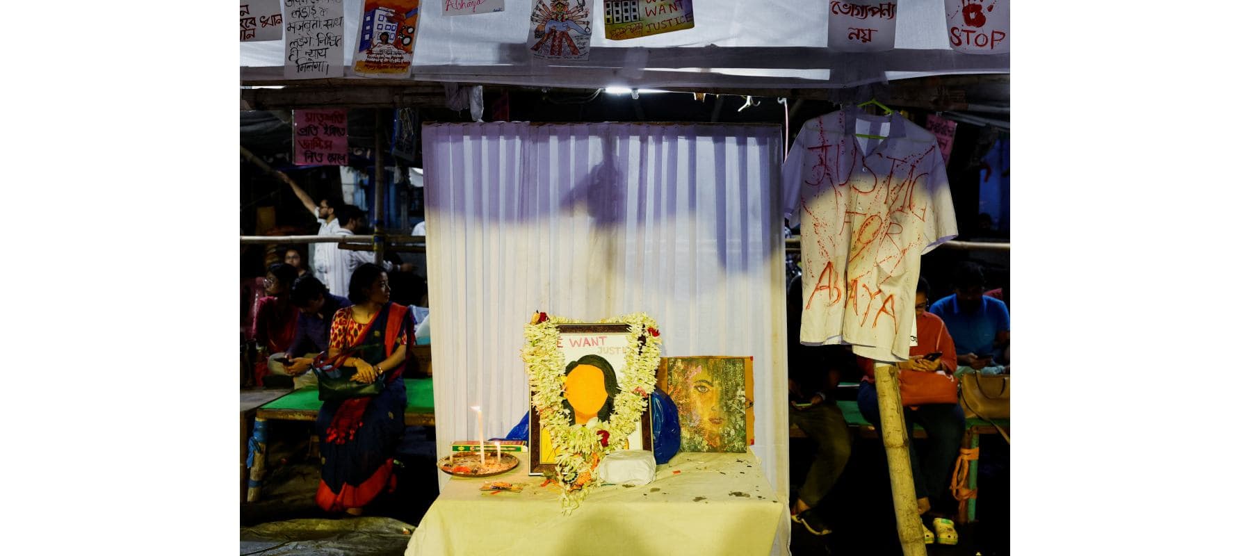 Medics sit behind an altar of framed images as they attend a protest condemning the rape and murder of a trainee medic, inside the premises of R G Kar Medical College and Hospital in Kolkata, India, Aug.20, 2024.