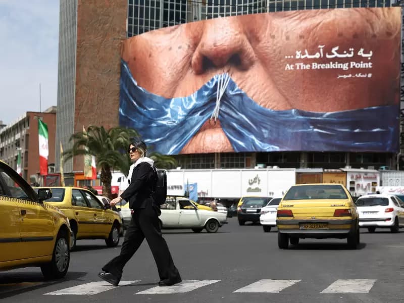 A woman walks past an anti-U.S. billboard depicting U.S. President Donald Trump and the Strait of Hormuz, in Tehran, Iran, May 2, 2026. Majid Asgaripour